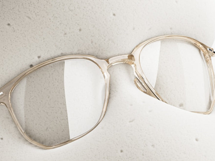 MUJOSH AQUA clear acetate eyeglasses frame resting on a stone surface, close up