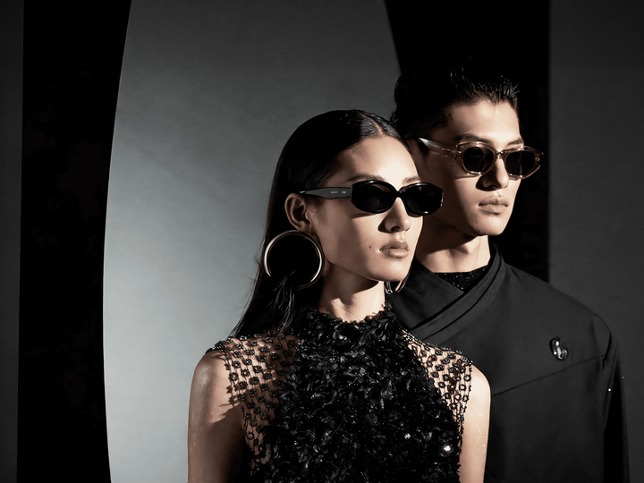 Two people wearing MUJOSH sunglasses in a dark editorial setting